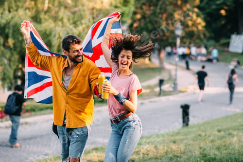Preview: Young couple dancing at a festival in the park with a United Kingdom flag