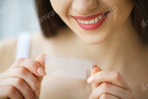 Preview: Teeth Whitening. Beautiful Smiling Woman Holding Whitening Strip. High Resolution Image