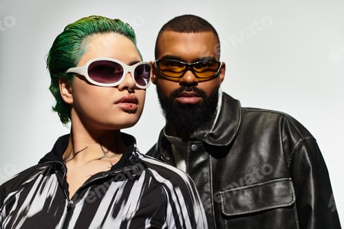 Preview: Stylish multicultural couple poses confidently in chic sunglasses indoors
