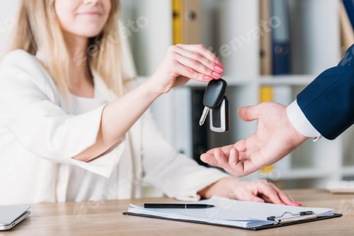 Preview: cropped shot of smiling woman taking car keys from businessman in office