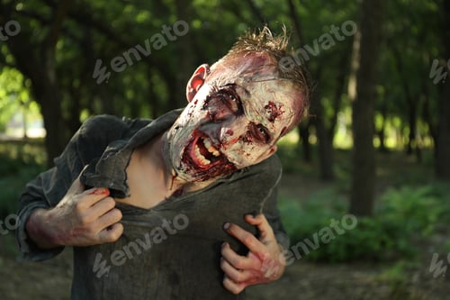 Preview: Scary zombie with bloody face outdoors. Halloween monster