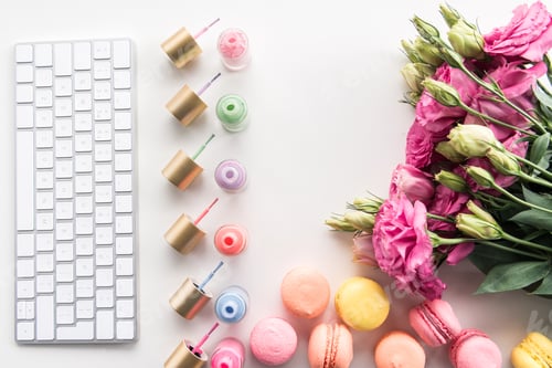 Preview: flat lay with keyboard, colorful nail polishes, macarons and flowers isolated on white