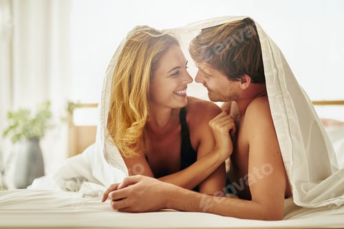 Preview: Shot of a young couple sharing an intimate moment under the covers in bed