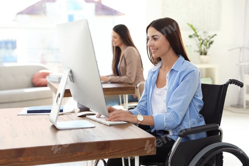 Preview: Young woman in wheelchair using computer at workplace