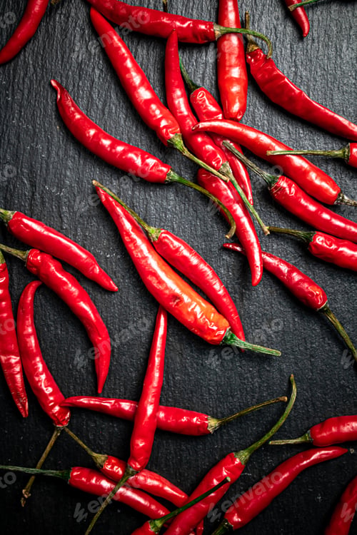Preview: Chili pepper pods on a stone board.