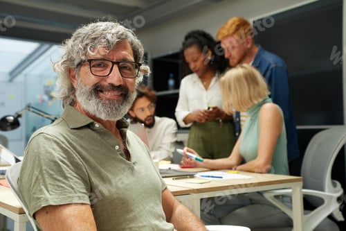 Preview: Portrait of office man smiling and looking at camera. In the background there is a group of people