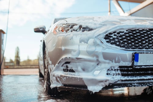 Preview: a gray sedan stands in soapy foam at a self-service car wash