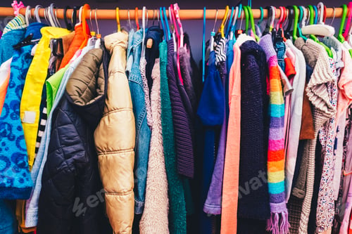 Preview: Colorful children's dresses hanging on hangers in a closet.