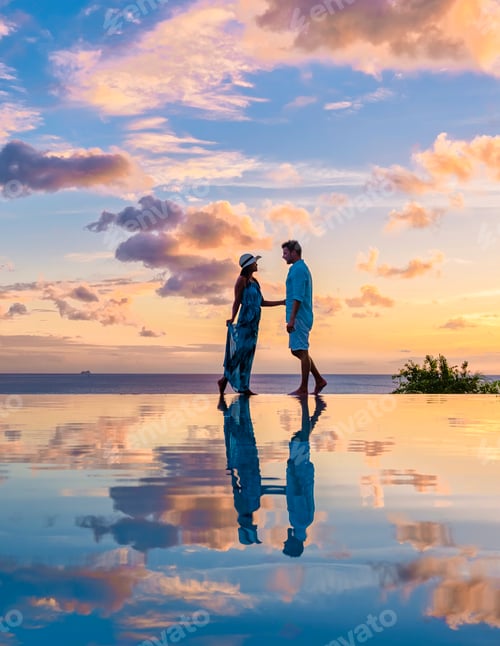 Preview: Young men and women watching sunset with reflection in the infinity pool at Saint Lucia Caribean