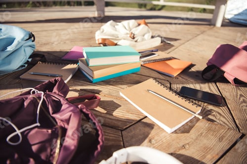 Preview: close-up view of books, backpacks and smartphone on wooden floor