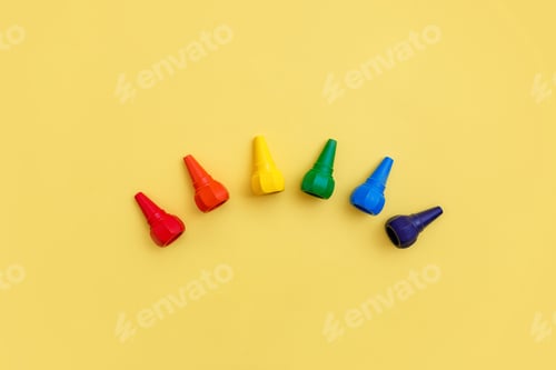 Preview: Kids wax crayons on bright yellow backgrouns. Top view.