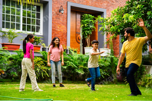 Preview: Indian family playing Langdi or one-leg hop game in garden, enjoying energetic outdoor fun