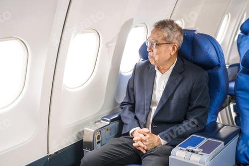 Preview: An adult male businessman sits by the window on a passenger plane, eager to travel abroad.