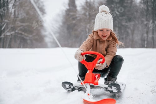 Preview: Happy little girl is enjoying winter snowfall outdoors