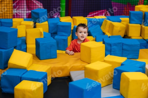 Preview: A boy child is playing in a game entertainment nursery. He plays with soft large cubes. Active