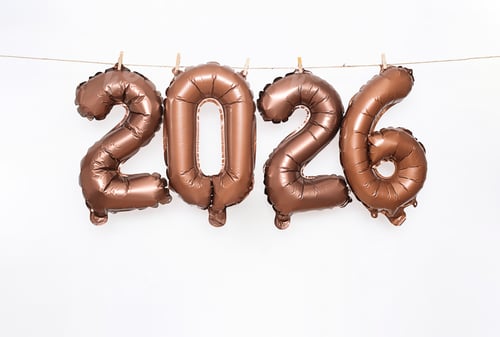 Visualização: Balões numéricos metálicos de bronze 2026 pendurados em corda com prendedores de roupa.
