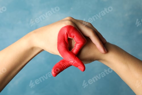 Preview: Two hands depict AIDS awareness sign against blue background, close up