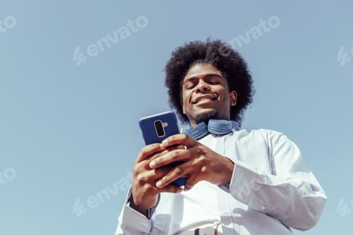 Preview: Happy afro guy using his mobile phone. View from below