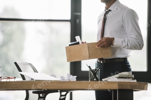Preview: cropped view of dismissed businessman holding wooden box in modern office