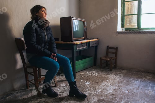 Preview: Young woman lonely in an abandoned ruined room with television. Loneliness concept