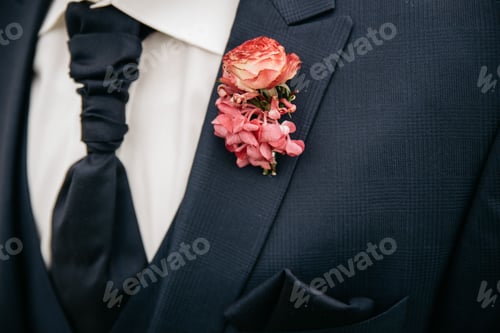 Preview: Closeup of the groom's black tie with a pink boutonniere on a black suit