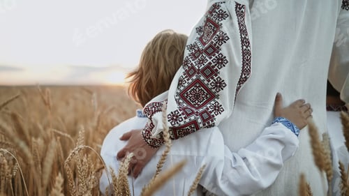 Preview: Mom hugs, strokes sons head.Unrecognizable ukrainian young family in wheat field