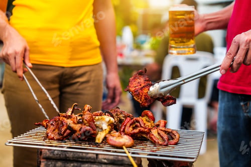 Preview: Barbecue with grilled chicken sausages. People in casual clothes are cooking and holding a glass