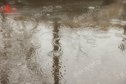 Preview: Rain drops falling down onto puddle outdoors