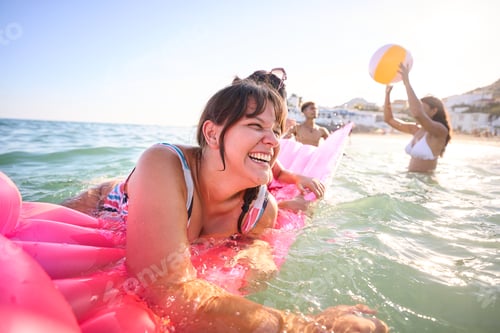 Preview: A group of diverse young friends in swimwear enjoying in the sea on the beach and playing