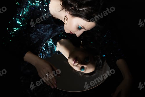 Preview: Beauty portrait of a woman with beautiful evening makeup and a mirror in her hands, a brunette girl