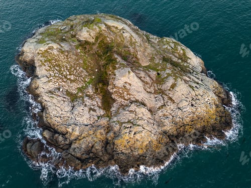 Visualização: Aerial View of Rocky Island in Coastal Waters Surrounded by Waves