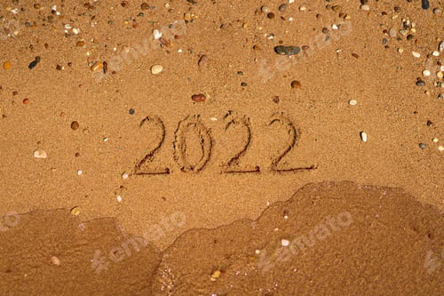 Preview: 2022 is drawing on sand on a beach with a wave by the sea. Vacation on the sea. New Year concept