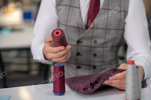 Preview: Hands of male tailor holding cloth and spool