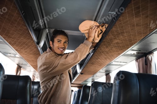 Vista previa: smiling young multiracial man putting rucksack on shelf in travel bus