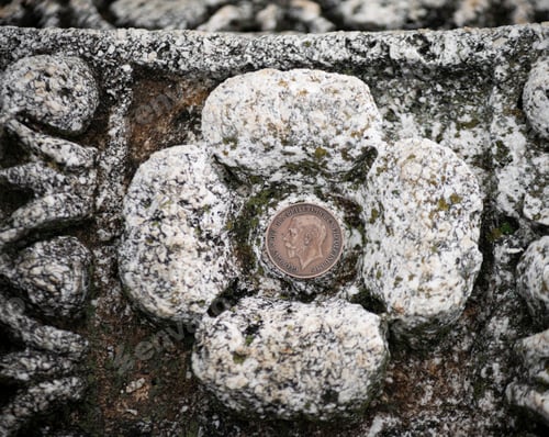 Preview: Close-up shot of an antique coin resting on a bed of snowy grey rocks
