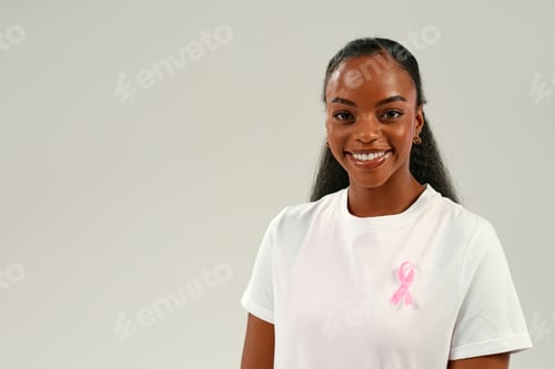 Preview: Smiling African American woman wearing pink ribbon, breast cancer awareness and support concept