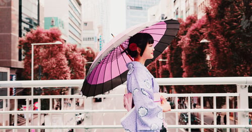 Preview: City, umbrella and woman in kimono walking on bridge with smile, morning travel or sightseeing adve