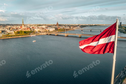 Preview: Aerial shot of Riga city with a big Latvian flag in the foreground at golden hour