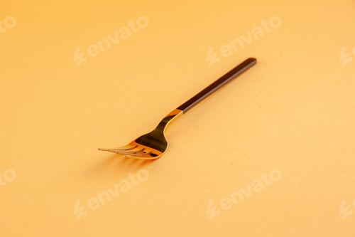 Preview: Close up view of elegant shiny stainless fork on golden background with free space