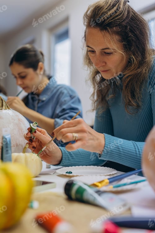 Preview: Children and adults painting pumpkins for Halloween, enjoying a fun and creative activity together.