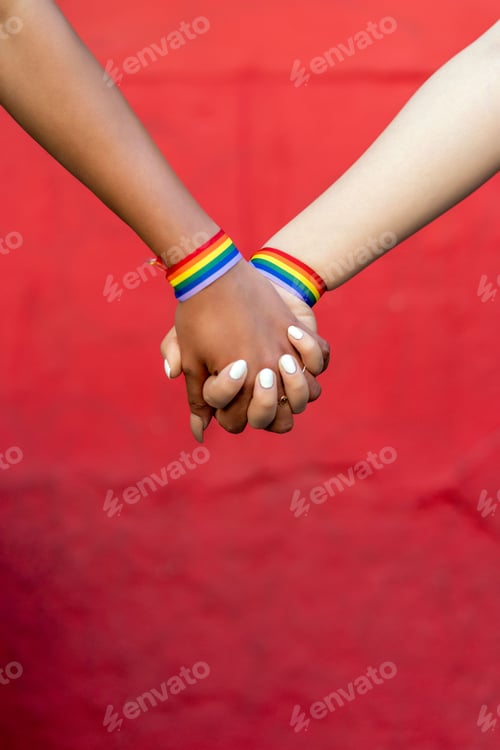 Preview: lesbia couple holding hands with gay pride bracelet