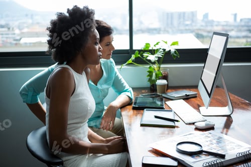 Preview: Female graphic designers looking at desktop pc