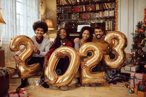 Visualização: Amigos felizes segurando balões enquanto comemoram o Ano Novo e olham para a câmera.