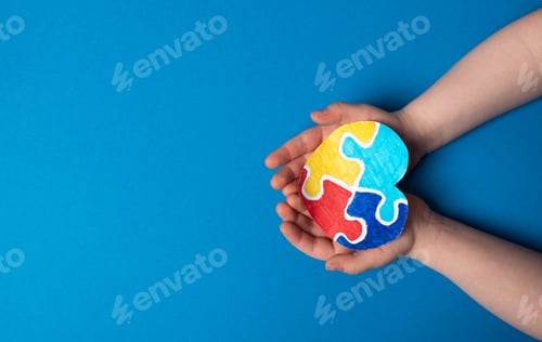 Preview: Child hands holding a puzzle heart on a blue background