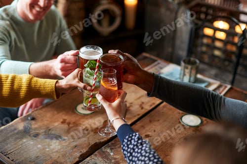 Preview: Close Up Of Friends Making Toast As They Meet For Lunchtime Drinks In Traditional English Pub