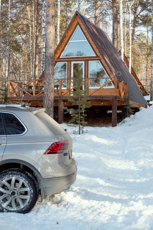Preview: Back of car of silver color standing in snowdrift on background of country house