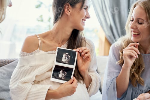 Preview: Caucasian pregnant woman showing the medical scan to her friends