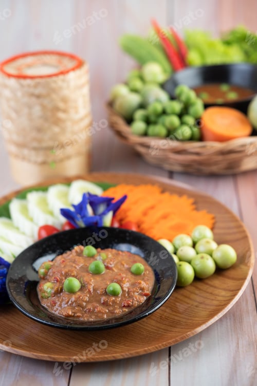 Preview: Chili paste paste in a bowl with eggplant, carrots, chili, cucumbers in a basket on wood table