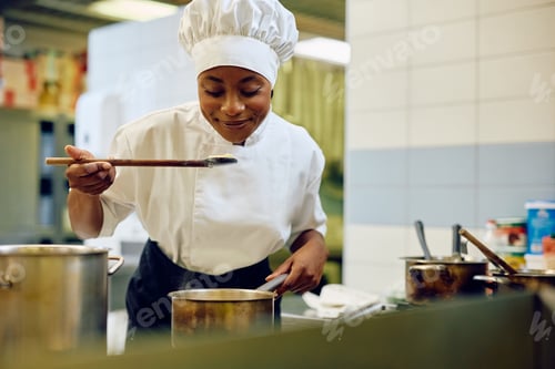 Preview: African American female chef cooking in the kitchen in a restaurant.