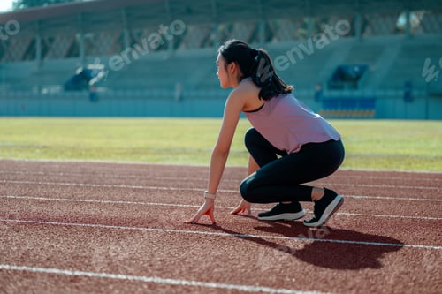 Preview: Young female athlete preparing for a race on running track in a stadium